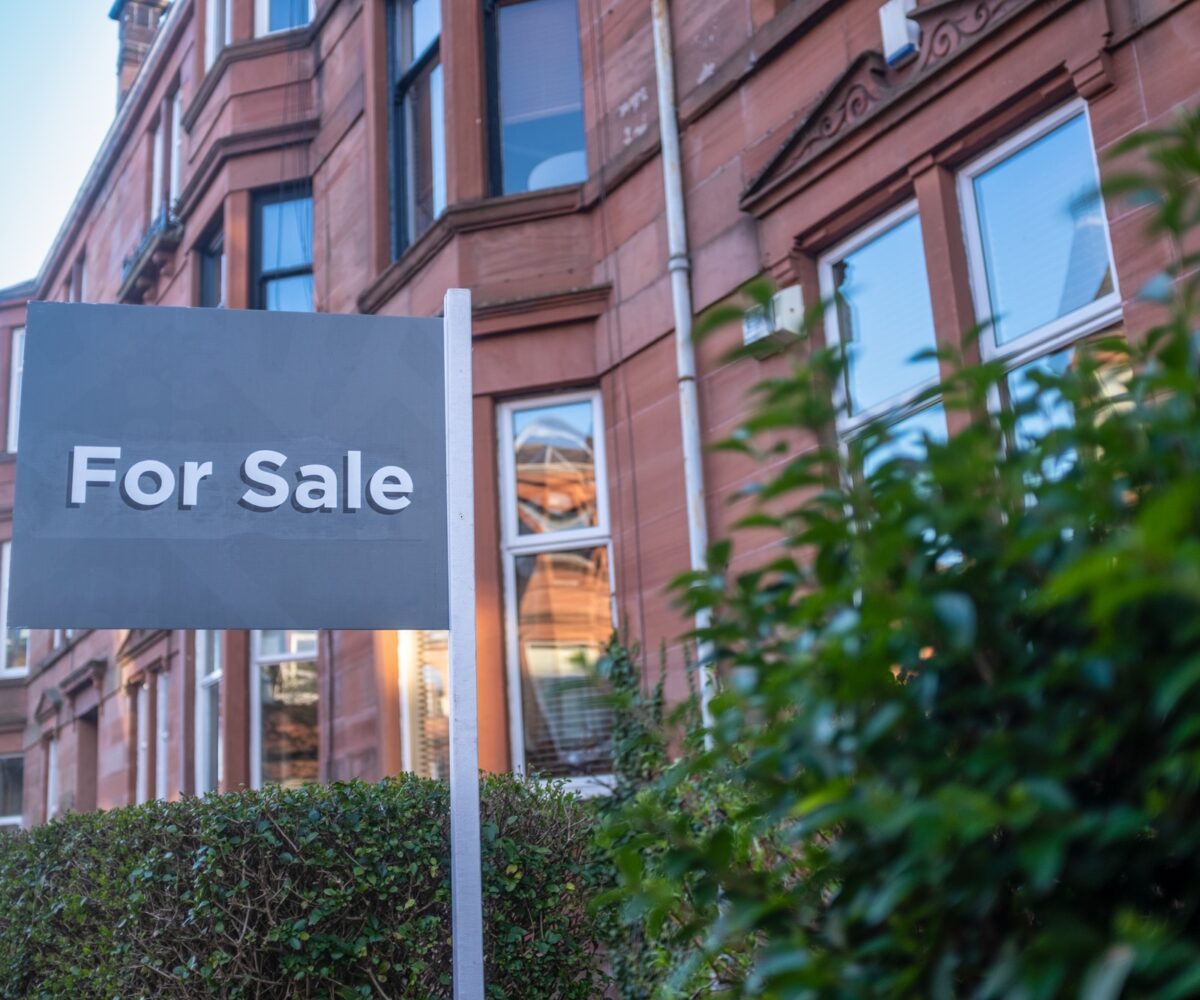 "For Sale" sign in front of building.