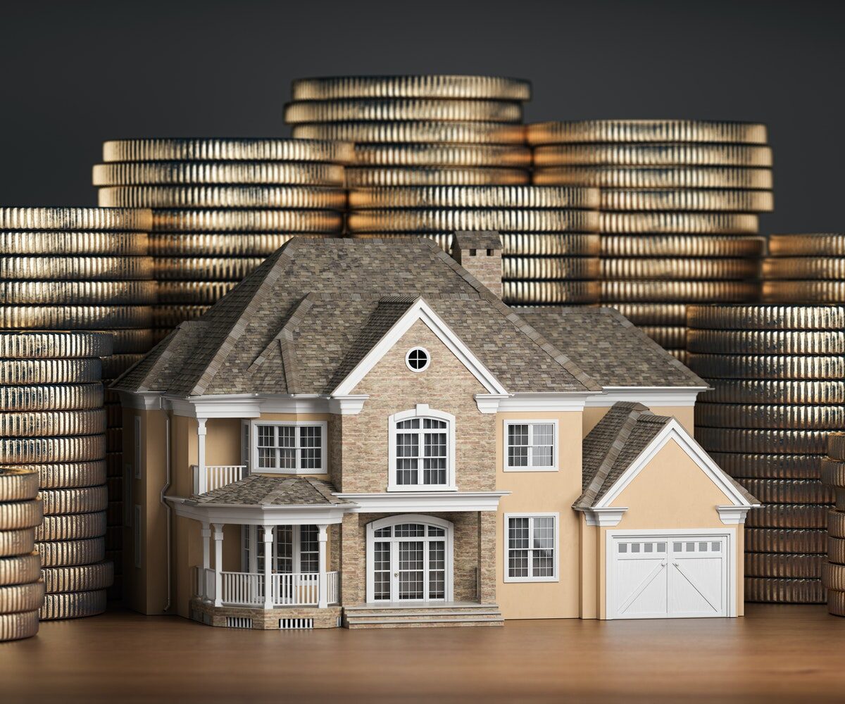 Model house surrounded by stacks of coins.