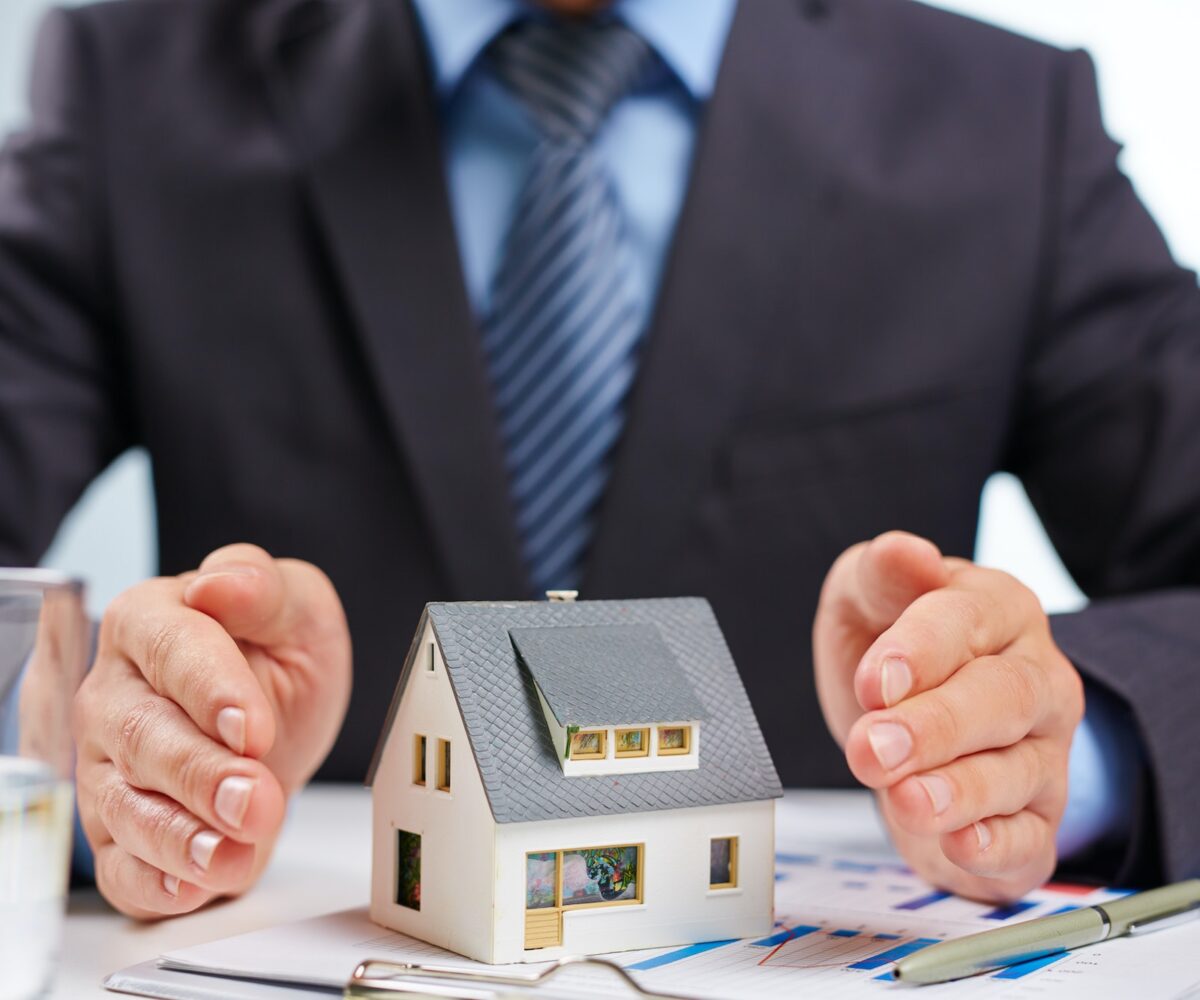 Businessman protecting a model house.